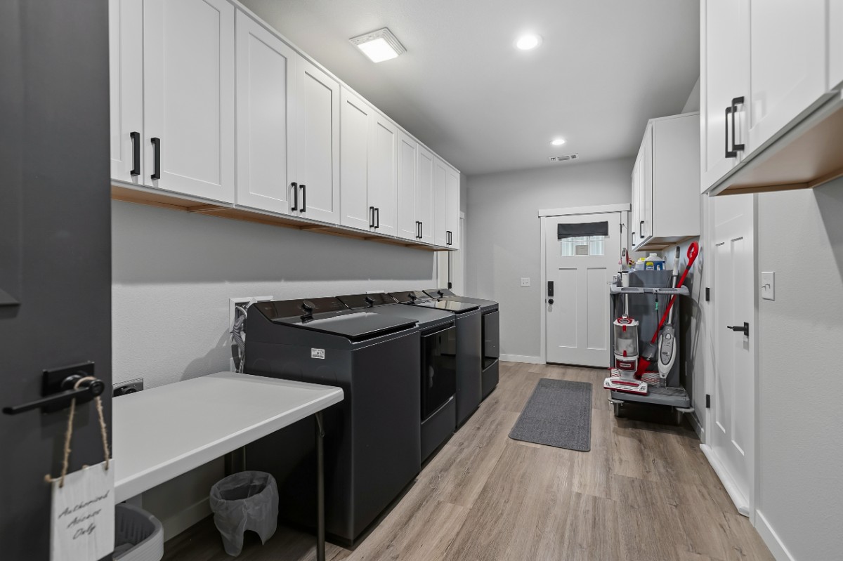 Laundry room with two washers and two dryers, folding counter and housekeeping cart