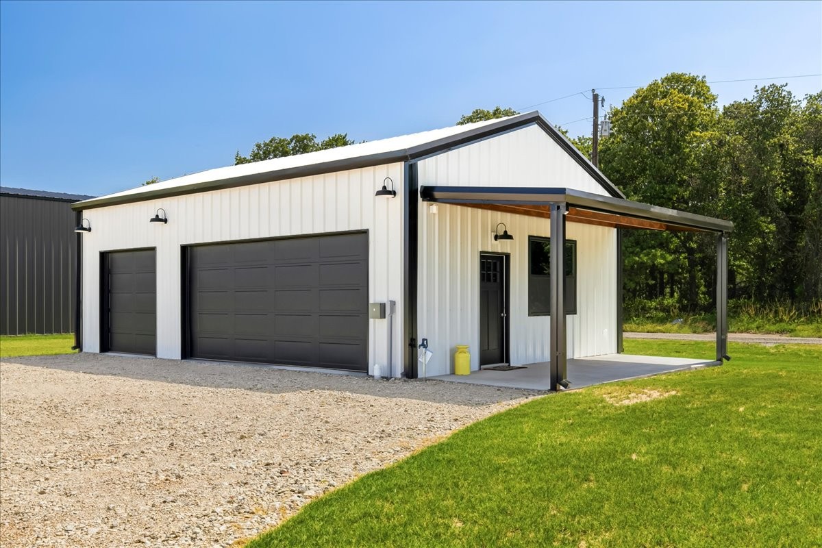 Shop building — two overhead doors, covered porch, gravel apron